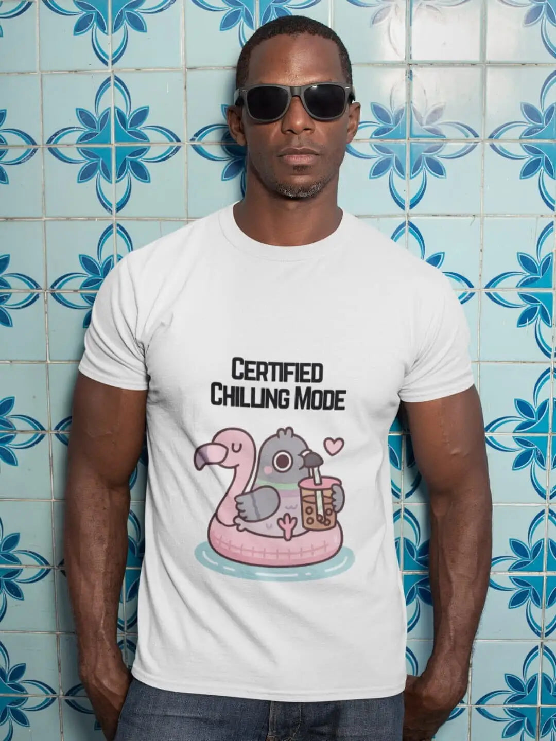 A white short-sleeved t-shirt with a cartoon graphic of a pigeon in a flamingo floatie drinking boba