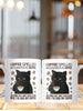 Two white ceramic coffee mugs with a grumpy black cat design