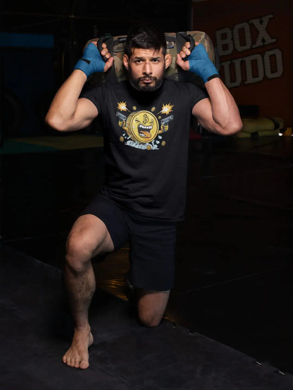 Man in workout attire with a sandbag on his shoulders