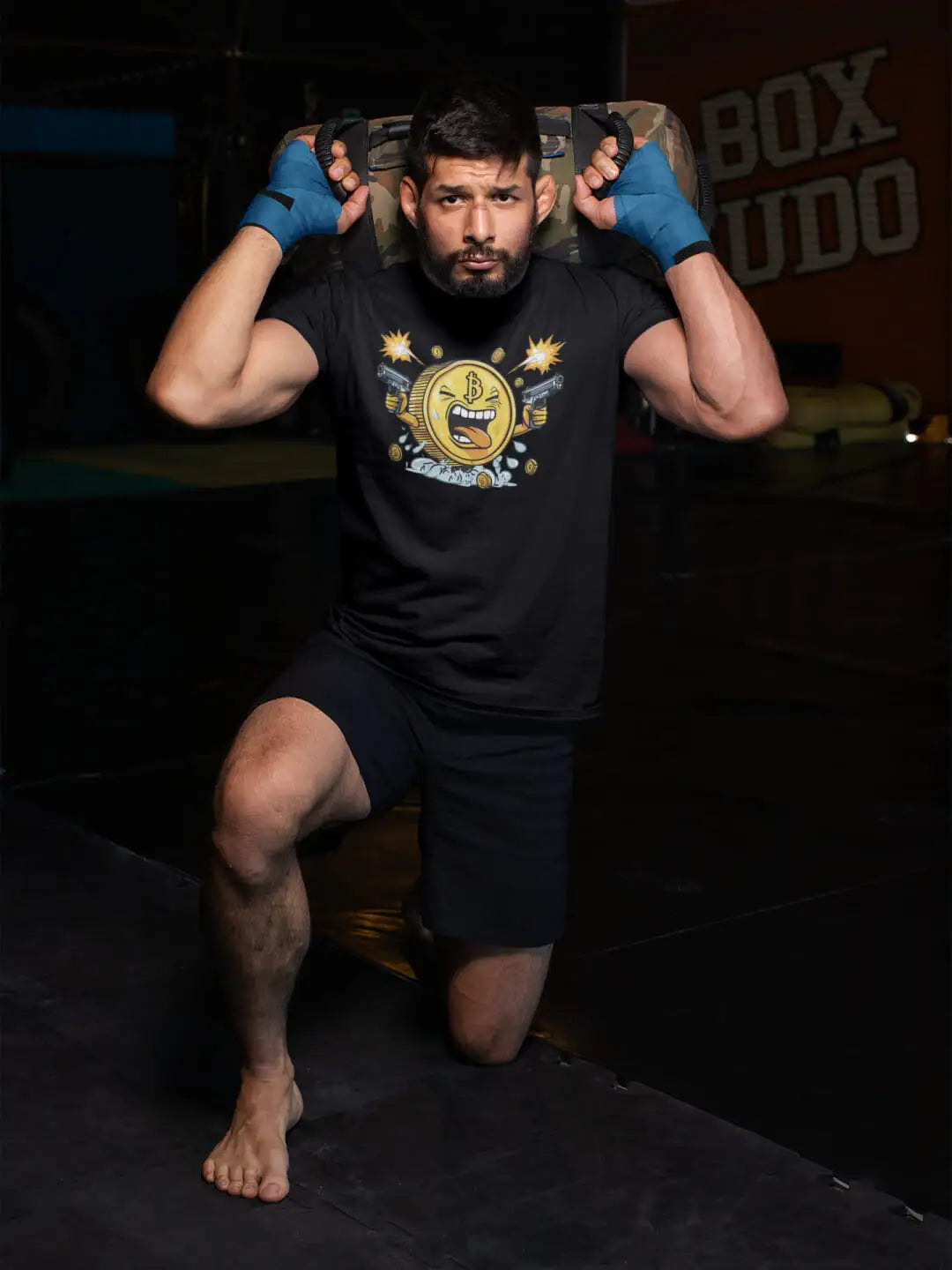 Man in workout attire with a sandbag on his shoulders
