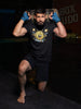 Man in workout attire with a sandbag on his shoulders