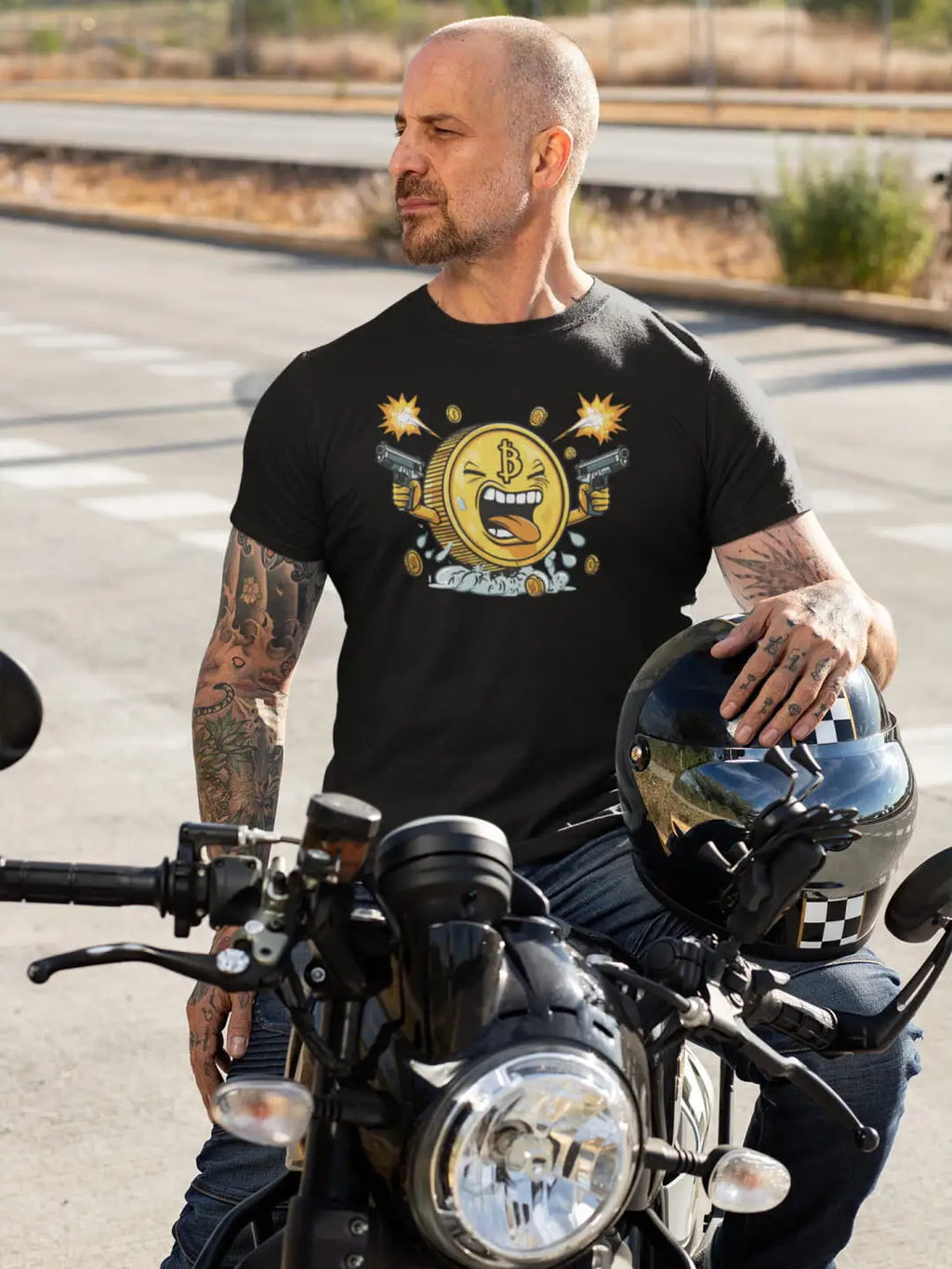 A man wearing a black t-shirt with a cartoon Bitcoin graphic and holding a motorcycle helmet
