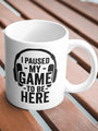 White ceramic mug with ’I PAUSED MY GAME TO BE HERE’ text and headphones graphic