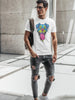 A man wearing a white t-shirt with a colorful dog graphic and ripped dark jeans