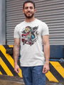 A man wearing a light grey crew-neck t-shirt with a colorful graphic print of a winged skeleton riding a skateboard, and blue cargo shorts
